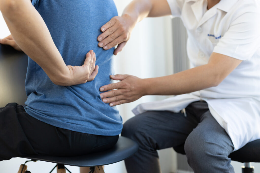 Doctor examining a patients back to assess autoimmune symptoms