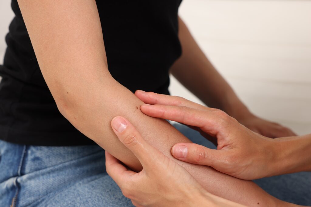 Doctor gently examining a patient's forearm and elbow joint, elbow pain diagnosis and treatment at Mast Health in Tampa