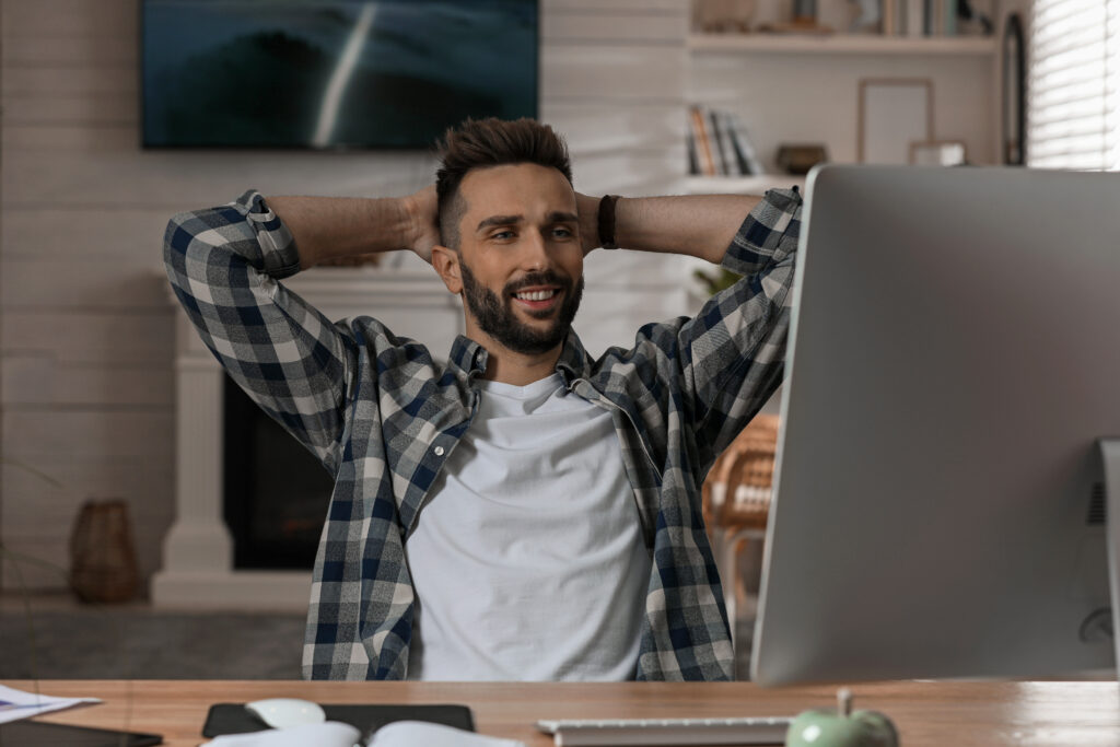 Man stretching with hands behind his head at his home office desk, headache and neck tension relief Mast Health offers Tampa patients