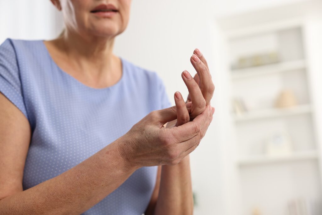 Mature woman rubbing her sore hand affected by arthritis