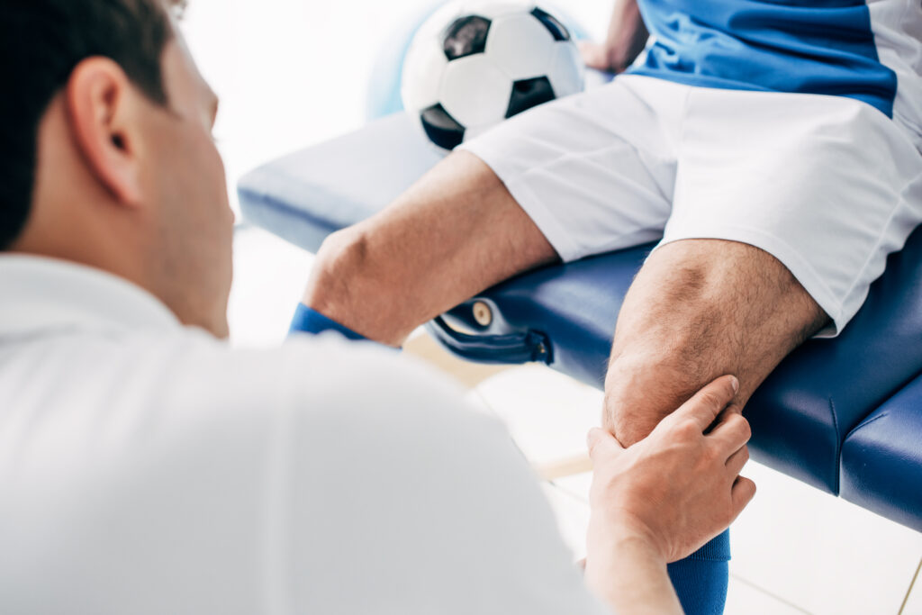 Physiotherapist massaging the leg of a football player in the clinic
