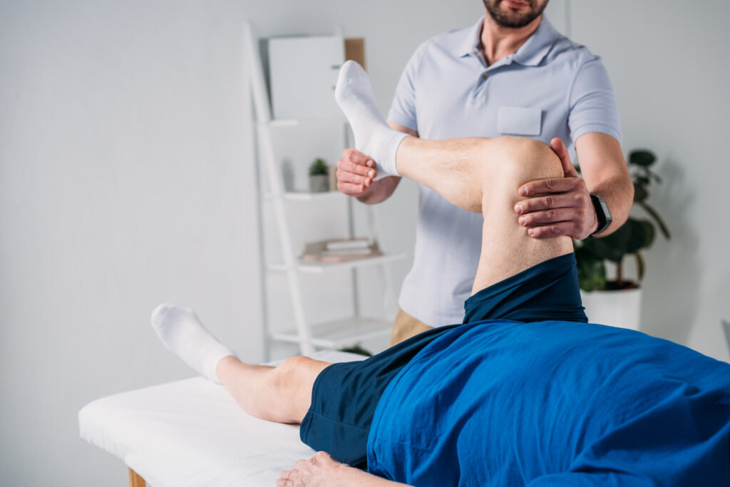 Rehabilitation therapist massaging a senior mans leg on a table