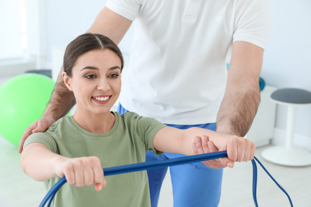Physiotherapist guiding a female patient through a gentle resistance band exercise, supportive fibromyalgia care at Mast Health in Tampa