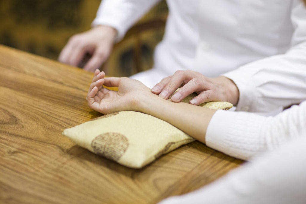 Senior doctor taking the pulse of a patient during an exam