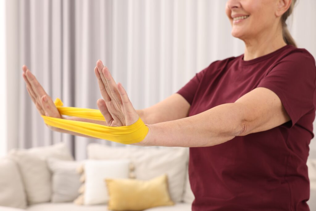 Senior woman exercising with a fitness elastic band at home
