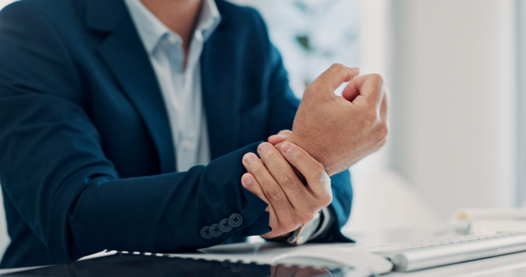 Businessman experiencing wrist pain from repetitive computer use