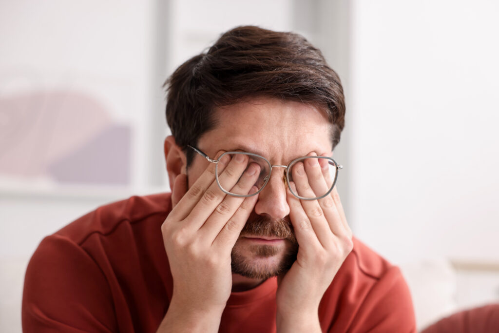 Man rubbing his tired eyes while wearing glasses, eye strain and tension headache relief at Mast Health in Tampa