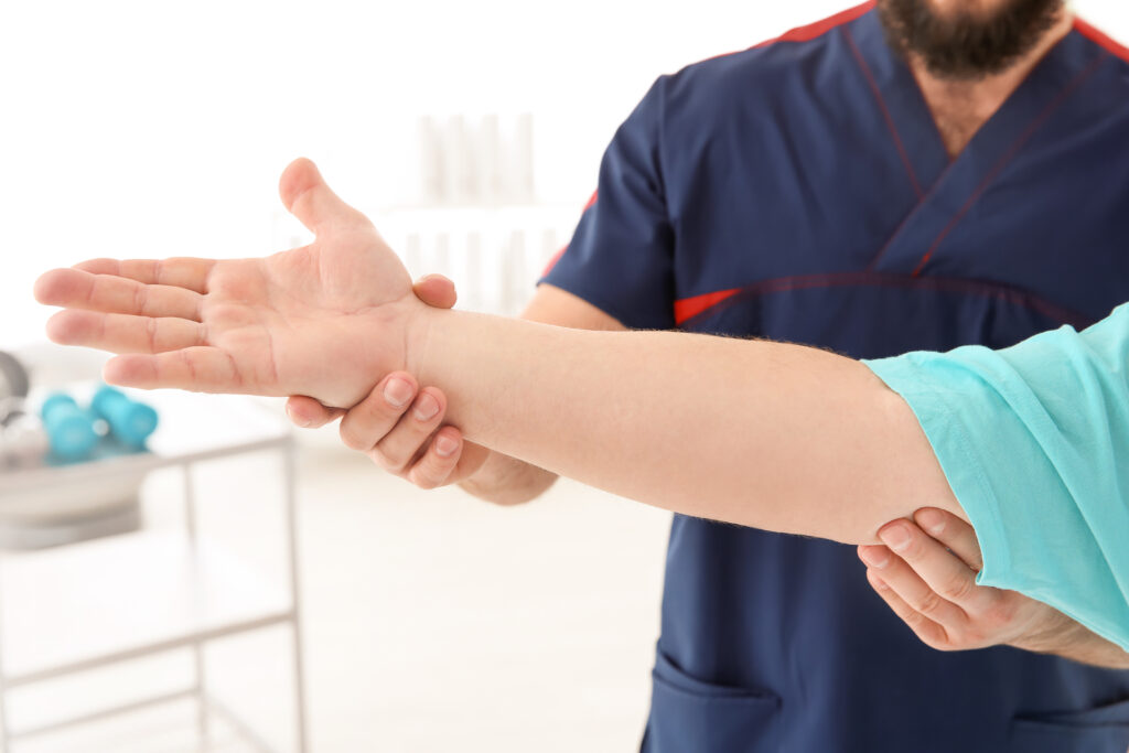 Physiotherapist holding a patient's wrist and forearm during a treatment session, restoring balanced arm movement for elbow pain at Mast Health in Tampa