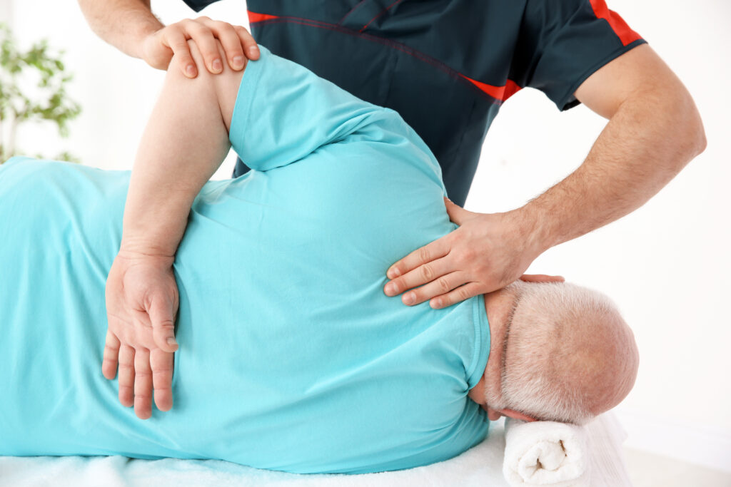 Physiotherapist gently mobilizing a senior patient's hip while lying on a treatment table, low force joint care for fibromyalgia at Mast Health in Tampa