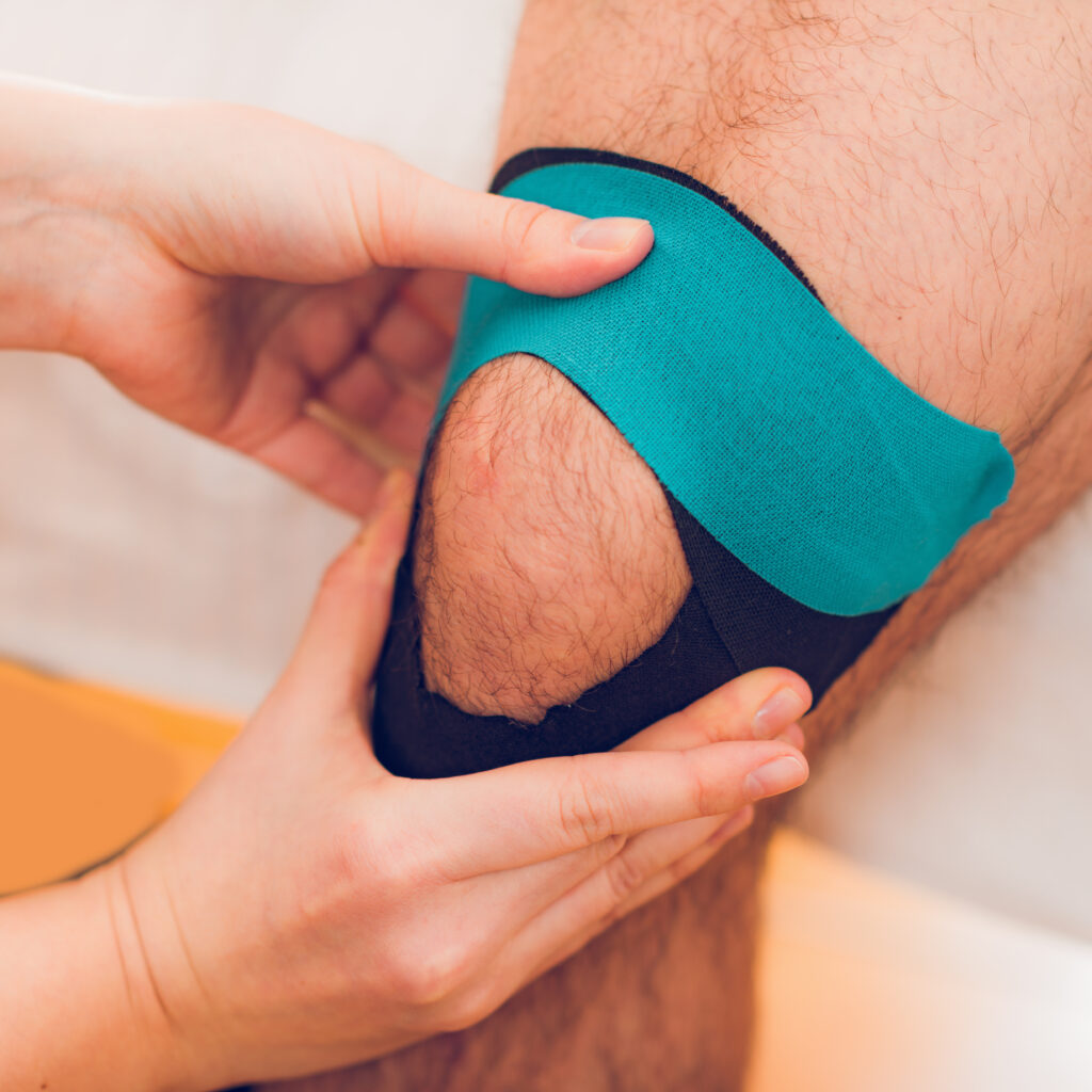 Kinesiology tape being applied to a patient's knee for support, knee pain Mast Health treats conservatively in Tampa