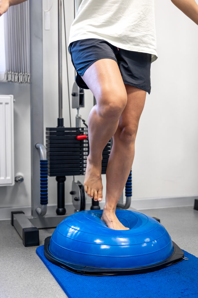 Person doing standing balance exercise on a bosu ball in a gym, knee pain Mast Health builds knee stability for in Tampa
