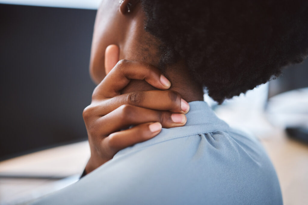 Stressed businesswoman rubbing her neck at the office, prolonged sitting contributing to a pinched nerve treated at Mast Health in Tampa, FL