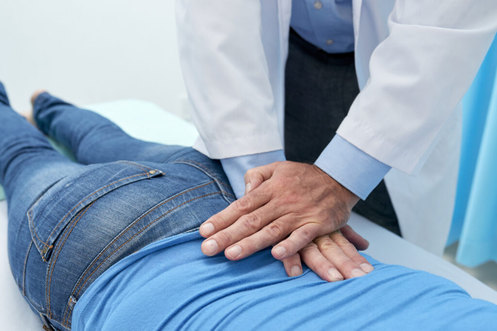 Chiropractor applying a hands-on spinal adjustment to a patient's lower back and hip to relieve hip pain at Mast Health in Tampa, FL