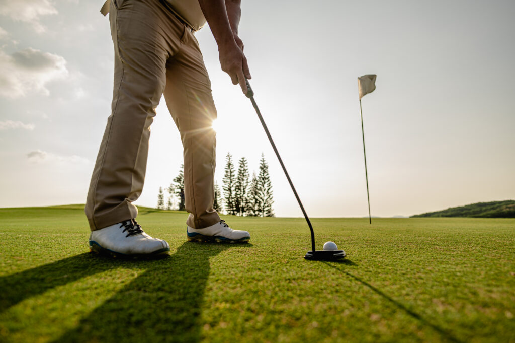 Golfer lining up a putt on the green at sunset, golfer's elbow is an overuse injury Mast Health treats in Tampa