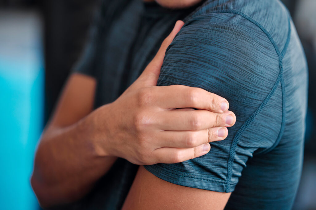 Man holding his shoulder in pain during a gym workout, a rotator cuff injury symptom treated at Mast Health in Tampa, FL