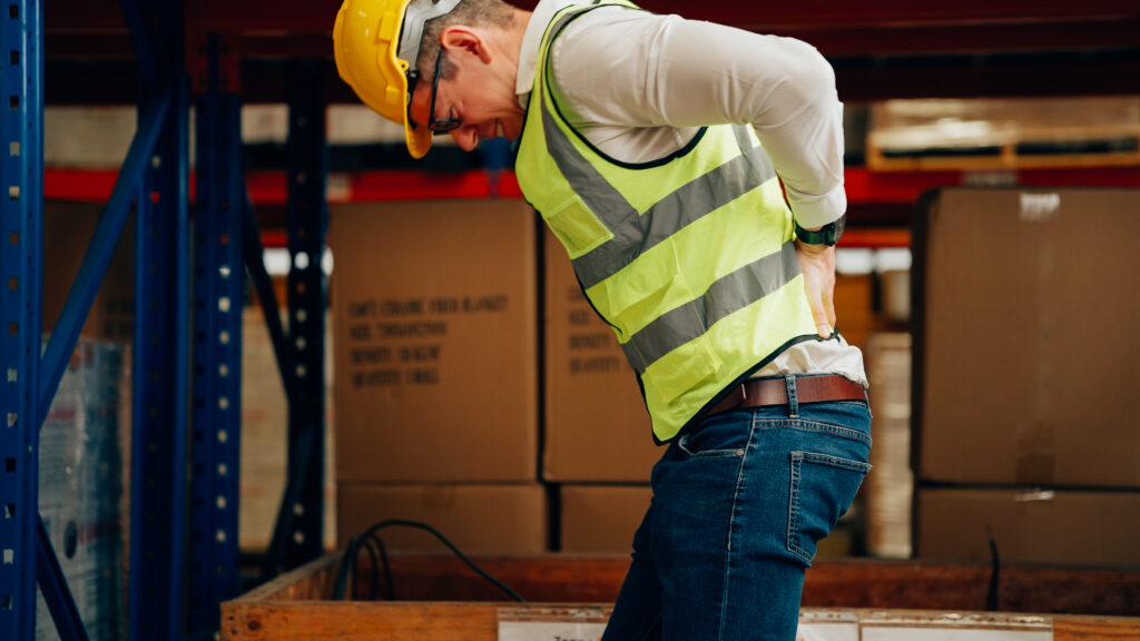 Male warehouse manager suffering from back pain on the job in Tampa