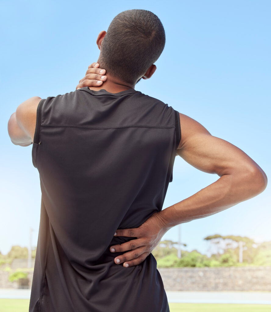Man from behind holding his neck and upper back after exercising outdoors, back pain relief Mast Health offers active Tampa patients
