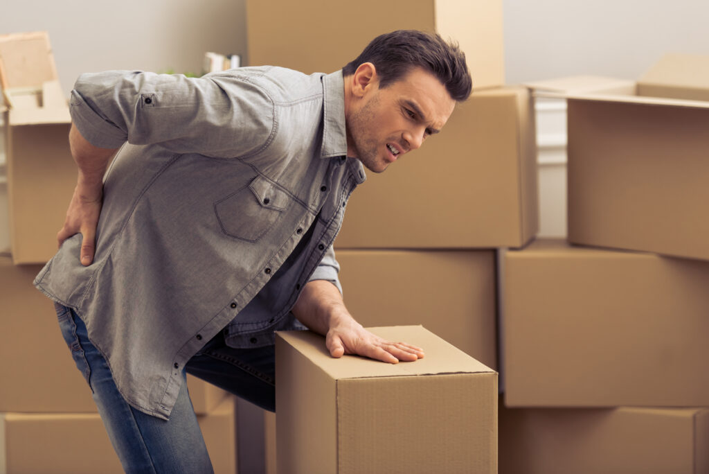 Man lifting a box while experiencing sudden back pain from a work injury