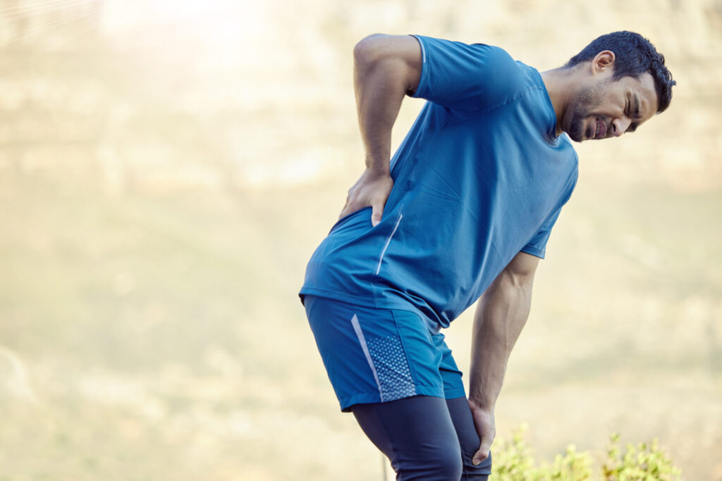 Man in athletic wear suffering from back pain outdoors in Tampa FL