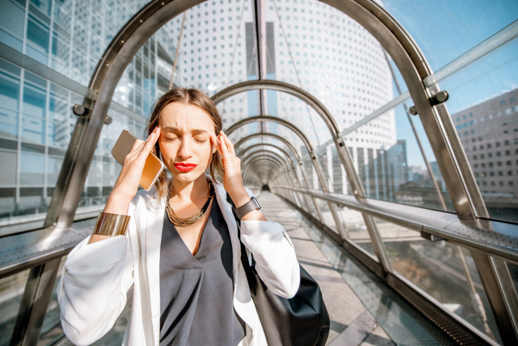 Overworked businesswoman pressing her temples on a city walkway, a vertigo and dizziness symptom treated at Mast Health in Tampa, FL