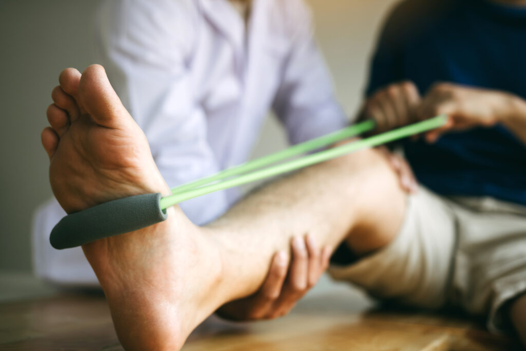 Physical therapist assisting a patient with a resistance band leg stretch, supportive nerve care Mast Health offers for neuropathy in Tampa