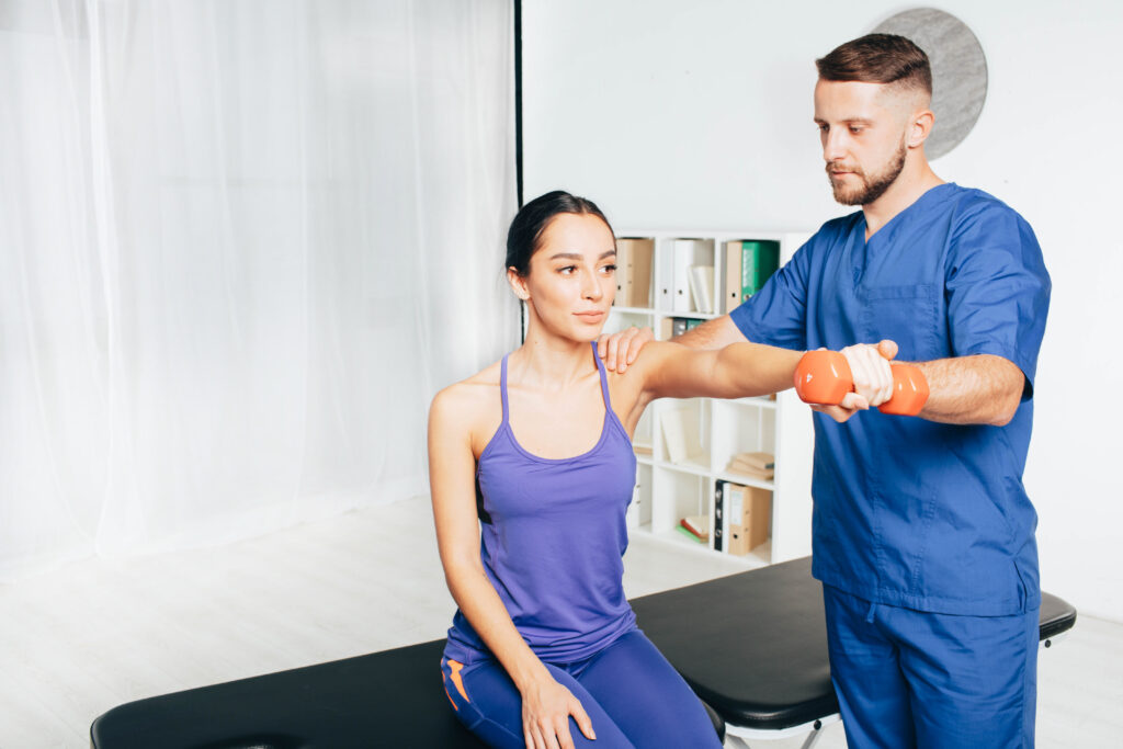 Physical therapist guiding a female patient lifting a dumbbell to strengthen her arm, rehab for an overuse injury Mast Health treats in Tampa
