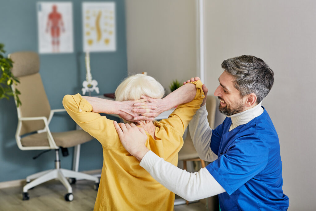 Chiropractor performing manual back and posture correction therapy on a senior woman at Mast Health in Tampa, FL