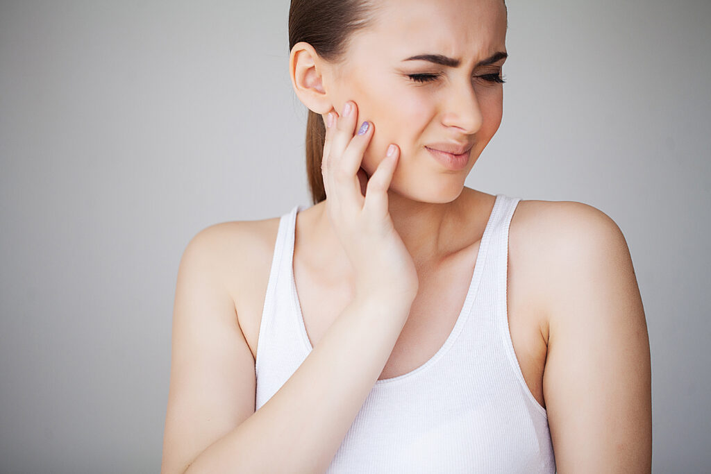 Woman holding her jaw in pain, a common TMJ and facial pain symptom treated at Mast Health chiropractic clinic in Tampa, FL