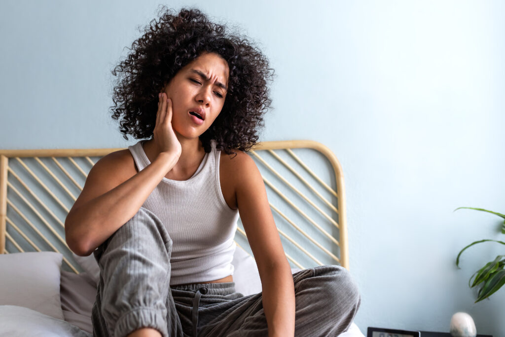 Young woman touching her cheek in pain, jaw and TMJ discomfort treated at Mast Health chiropractic clinic in Tampa, FL