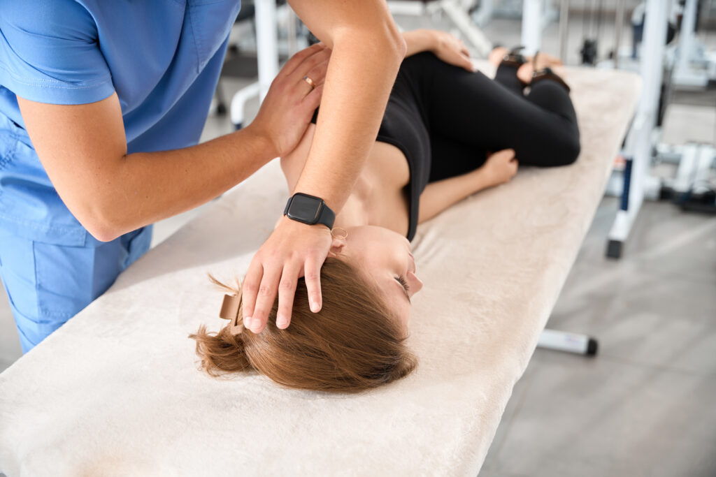 Woman lying on a treatment table receiving gentle neck therapy from a chiropractor, supporting vertigo relief at Mast Health in Tampa, FL