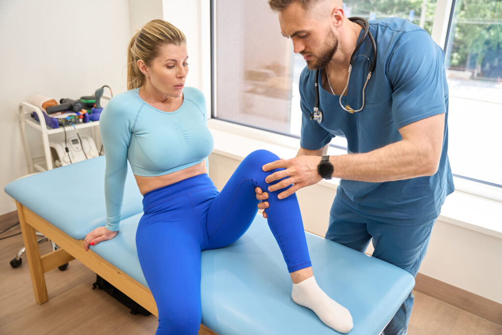 Doctor examining a patient's knee after a fall, evaluating for an overuse injury Mast Health treats in Tampa