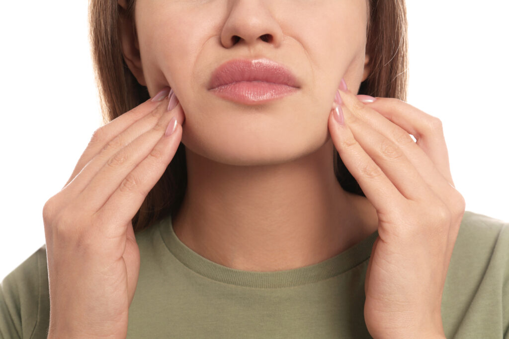 Close-up of a woman pressing her fingers to her jaw in discomfort, TMJ and jaw pain treatment at Mast Health in Tampa, FL