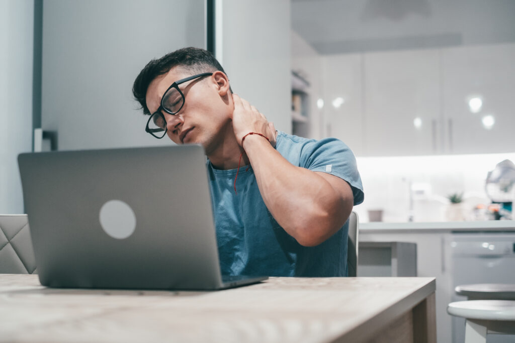 Young man massaging a stiff neck from desk work injury in Tampa